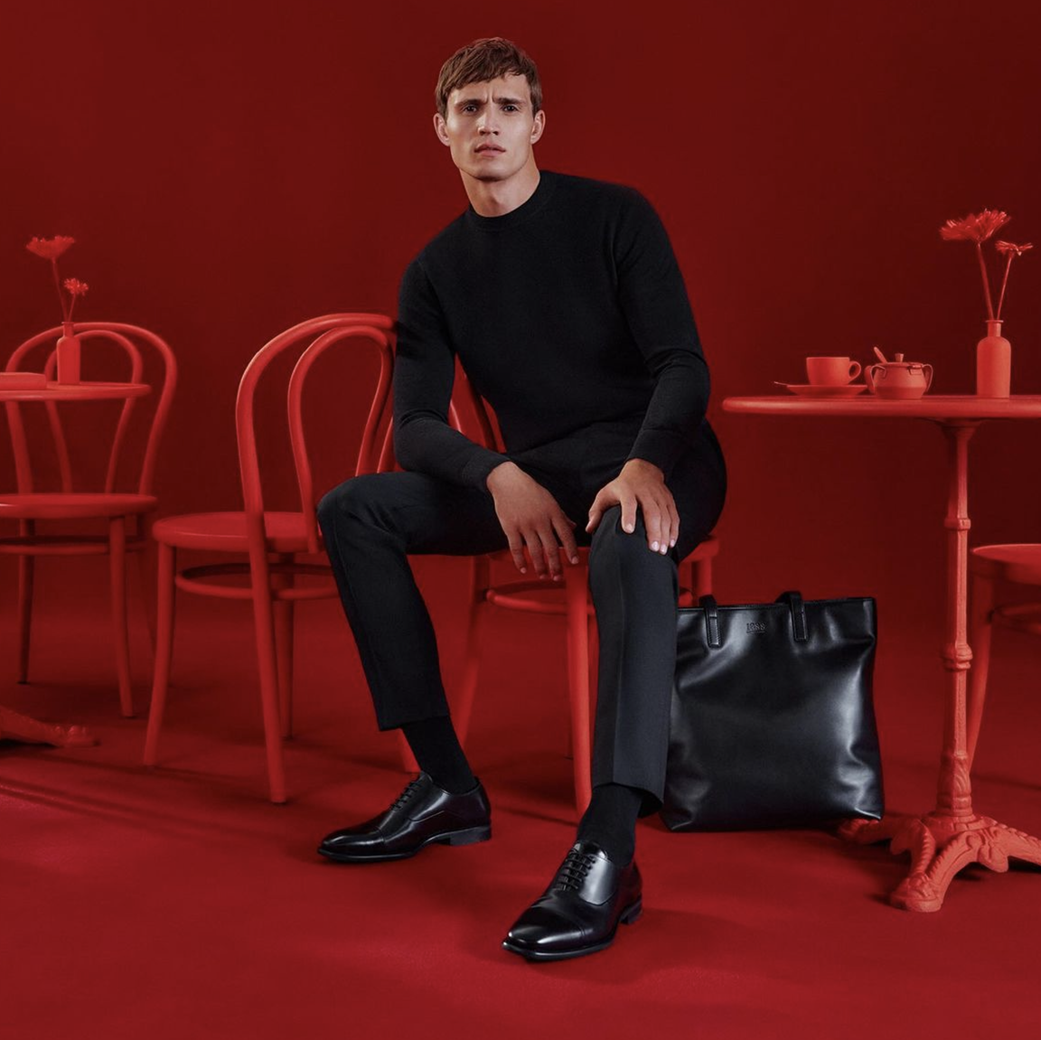 A striking image showcasing a Caucasian male model, against a stylish all-red backdrop, including a red table, red chair, and red room décor.