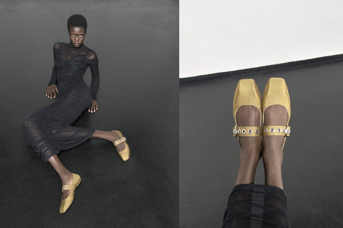 Ajah Angau reclining on a black floor in a ruched sheer black dress and gold Mary Jane flats, captured in raw studios’ minimalist space for aeyde Pre-Spring 25.