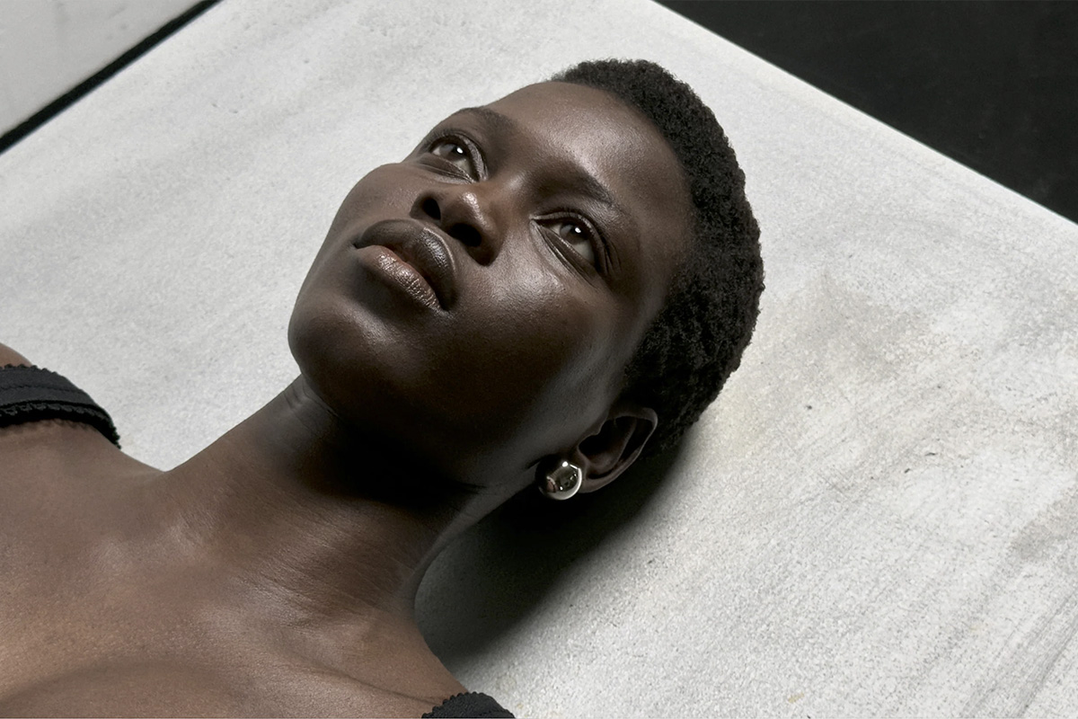 Close-up of Ajah Angau lying on a white textured surface, looking upward – a detail shot for aeyde’s Pre-Spring 25 campaign filmed at raw studios.