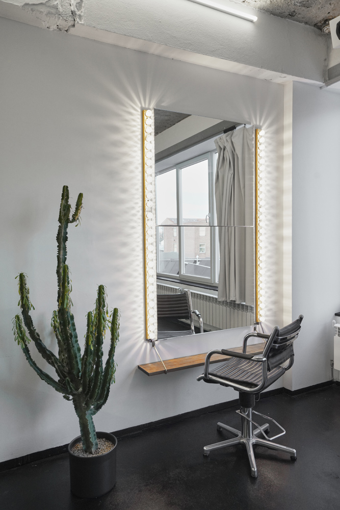 raw_studios_studio3_hair&makeup_DE Make-up-Bereich in Studio 3, einem Fotostudio in Berlin, mit beleuchtetem Spiegel, Friseurstuhl und Kaktus – perfekt für Styling und Vorbereitung