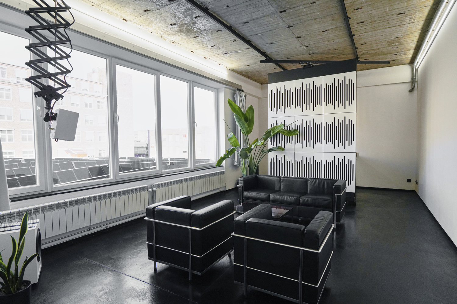 raw_studios_studio3_loungearea1_DE Loungebereich in Studio 3, einem kreativen Mietstudio in Berlin, mit modernen Ledersesseln, Akustikwand und viel Tageslicht durch große Fenster