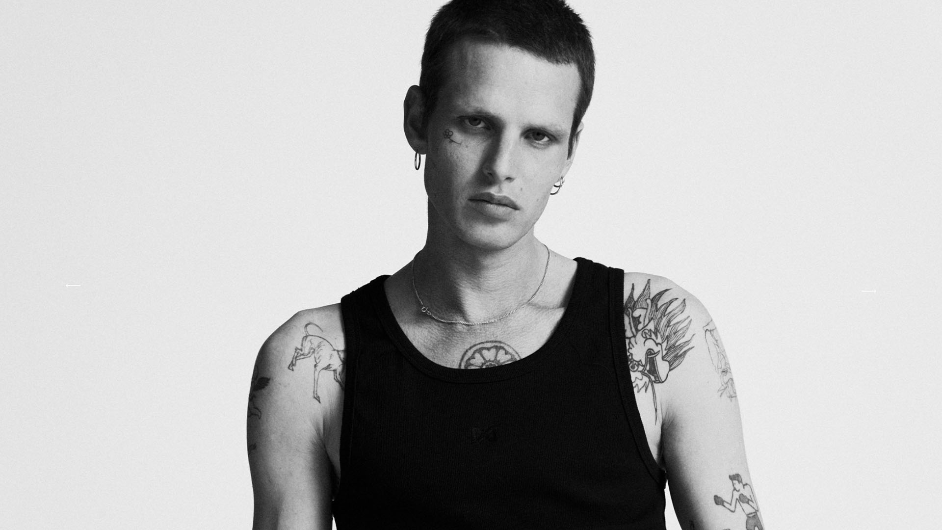 Tattooed model in black tank top from nowrubi capsule collection, photographed by Bert Spangemacher at raw studios – photoshoot in Berlin photo studios.